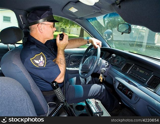 Police officer in his squad car, talking on his radio.