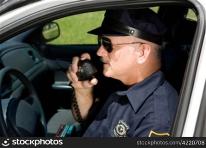 Police officer in squad car talking on his radio. Closeup view.