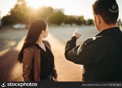 Police officer in uniform shows parking place to female driver. Law protection, car traffic inspector, safety control job. Police officer shows parking place to driver