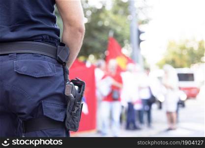 Police officer on duty during street protest, blurred protesters in background