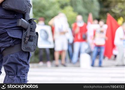 Police officer on duty during street protest, blurred protesters in the background