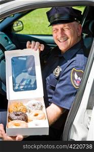 Police officer sitting in his squad car with a box of donuts.