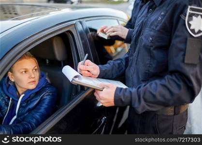 Police patrol checking driver&rsquo;s license of female driver. Policemen in uniform protect the law, registration of an offense. Cops work on city street, order and justice control. Police patrol checking driver&rsquo;s license of driver