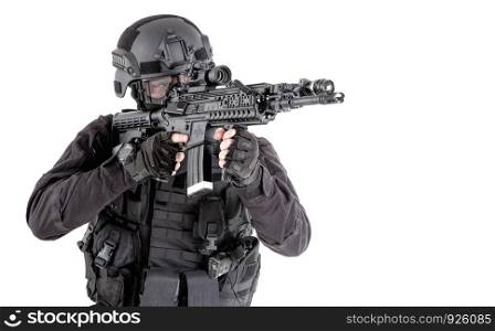 Police special forces, SWAT team fighter in tactical ammunition and armor, aiming weapon, observing suspect movements, controlling sector with optical sight on service rifle isolated studio shoot. Police SWAT team fighter aiming assault rifle