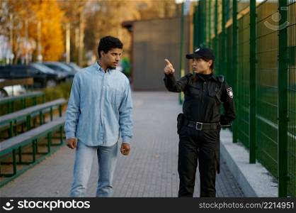 Police woman showing way to man. Young male passerby citizen asking direction on street. Police woman showing way to man passerby
