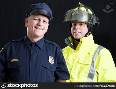Policeman and fireman both photographed against a black background.