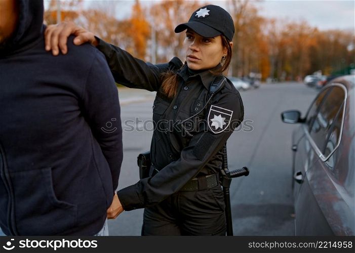 Policewoman arresting man car thief or drug dealer on city road. Female cop leading offender. Policewoman arresting man car thief on road