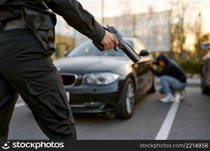 Policewoman holding gun with car thief on blurred background. View from police officer back. Policewoman holding gun at car thief backview