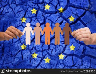policy, crisis and national security concept - hands holding chain of multiracial people over flag of europe on cracked ground background. hands holding chain of people over flag of europe