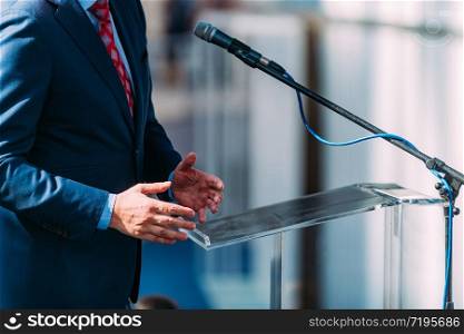 Political campaign. Senior politician on stage, speaking into microphone during election campaign. Male Speaker On The Stage