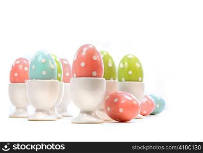 Polka dot easter eggs in cups on white background