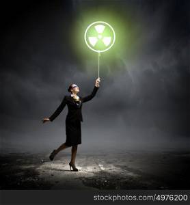 Pollution concept. Image of businesswoman in goggles holding balloon with radioactivity symbol