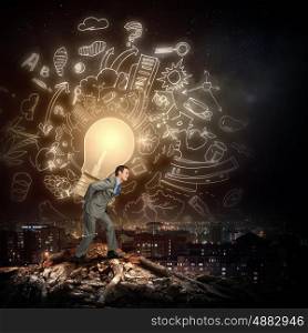 Pollution concept. Young man on ruins carrying light bulb on back