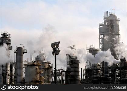 Pollution drifts across the industrial apparatus of a large oil refinery.