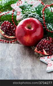 Pomegranate and apple with festive decorations over wooden background, selective focus, copy space