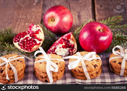 Pomegranate fruit, cookies and apples on wooden background