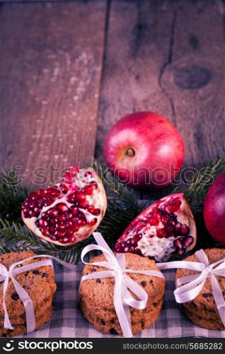 Pomegranate fruit, cookies and apples on wooden background
