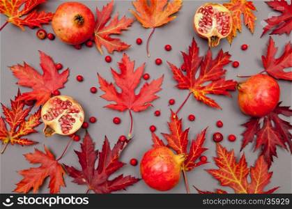 Pomegranates and autumn red fallen leaves pattern on grey background