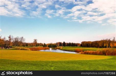 Pond in autumn park, trees with colorful foliage. Yellow forest and lake, nature panoramic landscape in sunny day. Pond in autumn park, trees with colorful foliage