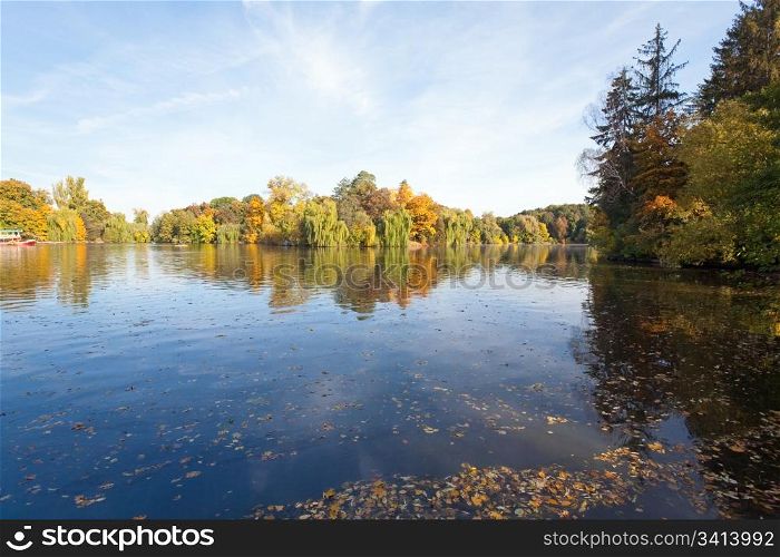 Pond water surface with reflection of colorful trees in autumn park