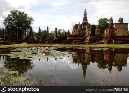 Pond with lotuses a nd ruins of wat Mahathat, Sukhotai, Thailand