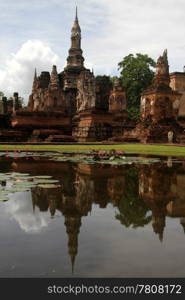 Pond with lotuses a nd ruins of wat Mahathat, Sukhotai, Thailand