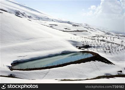 Pond with water and snow mountain near Quadisha valley in Lebanon