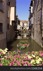 pont and boat flowered on a river bordered by houses