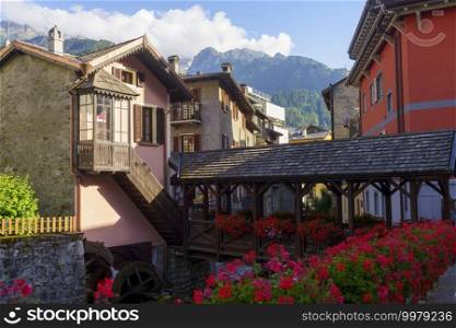 Ponte di Legno, Brescia province, Lombardy, Italy. old town in the Camonica valley. The wooden bridge and red flowers