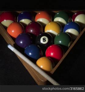 Pool balls in a rack with a pool cue