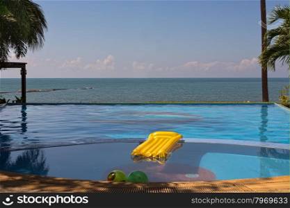 Pool overlooking the sea with yellow inflatable mattress.