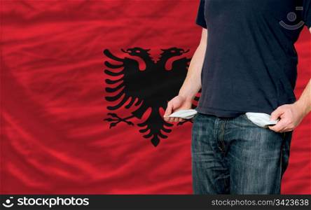 poor man showing empty pockets in front of albania flag