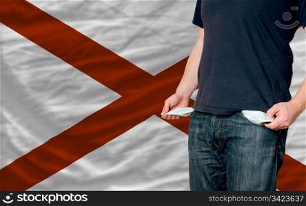 poor man showing empty pockets in front of american state of alabama flag