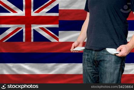 poor man showing empty pockets in front of american state of hawaii flag