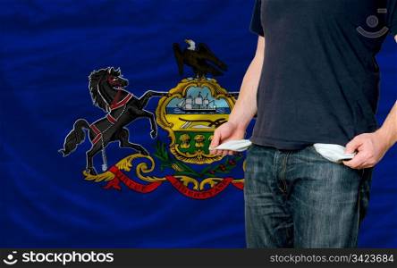 poor man showing empty pockets in front of american state of pennsylvania flag