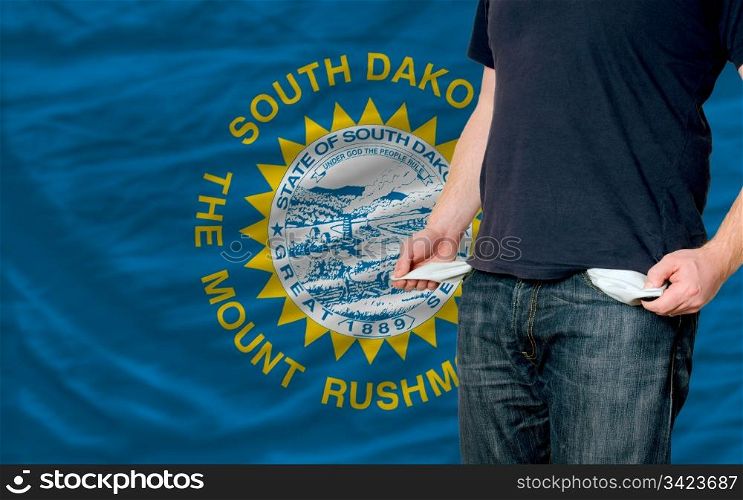 poor man showing empty pockets in front of american state of south dakota flag