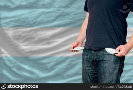 poor man showing empty pockets in front of arentina flag