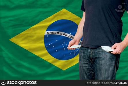poor man showing empty pockets in front of brazil flag