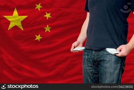 poor man showing empty pockets in front of china flag