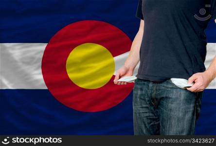 poor man showing empty pockets in front of colorado flag