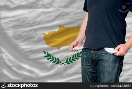 poor man showing empty pockets in front of cyprus flag