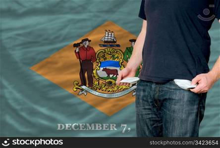 poor man showing empty pockets in front of delaware flag