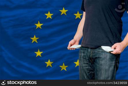 poor man showing empty pockets in front of europe flag