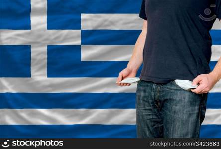 poor man showing empty pockets in front of greece flag