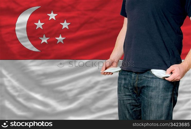 poor man showing empty pockets in front of singapore flag