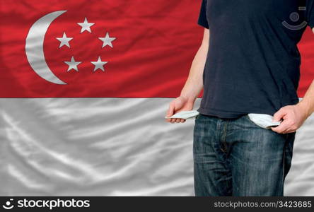 poor man showing empty pockets in front of singapore flag