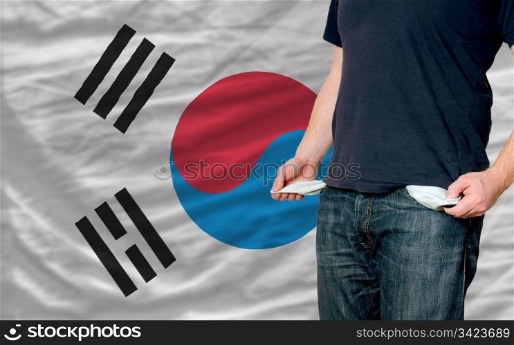 poor man showing empty pockets in front of south korea flag
