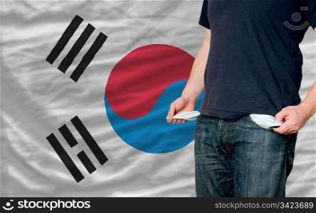 poor man showing empty pockets in front of south korea flag