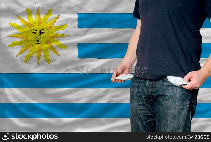 poor man showing empty pockets in front of uruguay flag