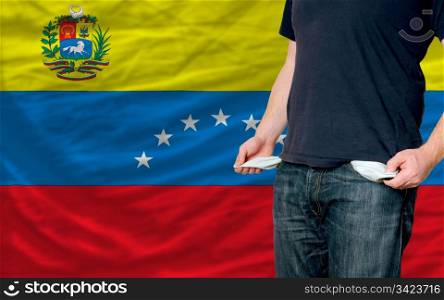 poor man showing empty pockets in front of venezuela flag